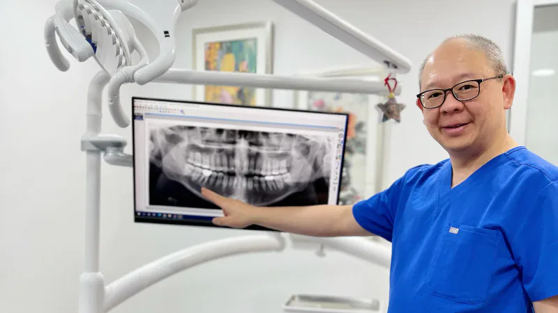 Lead Dentist Dr Eu Guan Koh pointing at an x-ray